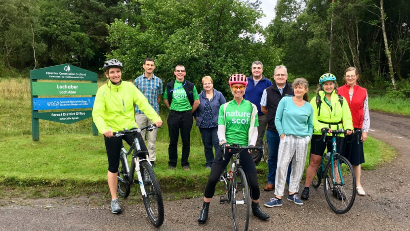 3 staff members on bikes, with other office staff at Fort William.