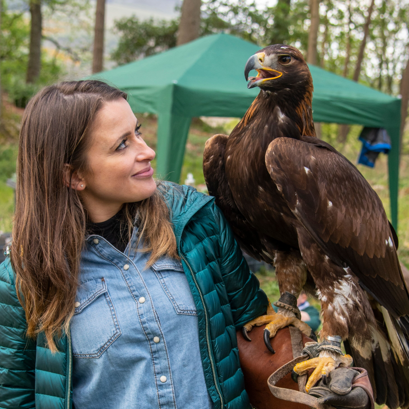 Lady wearing a gauntlet on her arm, with a golden eagle perched on it.