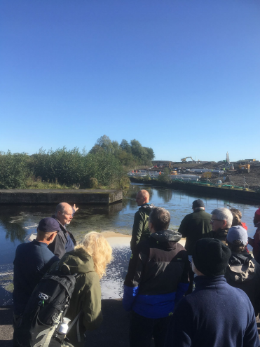 group of people being shown an area being built behind water