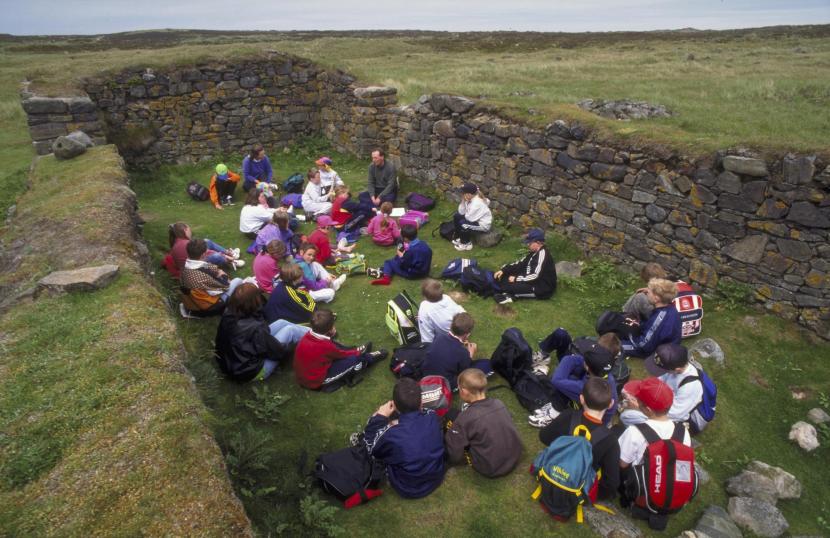 Children sitting inside an old stone age ruin