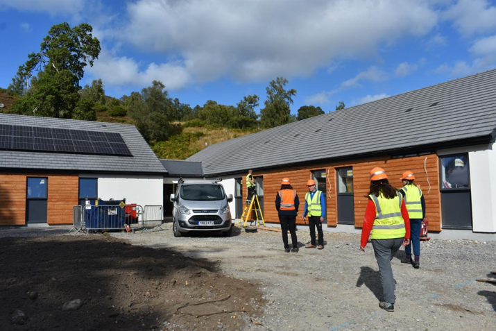 People in high vis vests and hard hats, stand talking outside the visitor centre, which is still under construction.