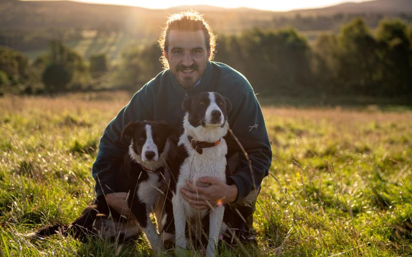 Fred swift with two dogs sitting in field