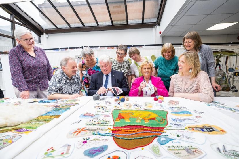 A group of people behind a tapestry