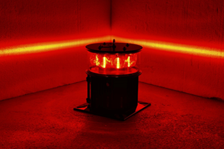 A medium intensity aviation obstruction warning light illuminated to a minimum of two thousand candela, and showing the focused horizontal nature of the emitted light beam