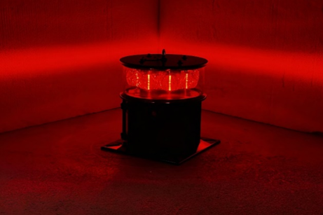A medium intensity aviation obstruction warning light illuminated to a minimum of two hundred candela, and showing the focused horizontal nature of the emitted light beam