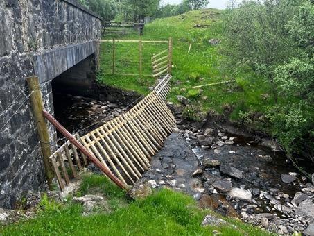 Wooden water gate on a small watercourse in front of a stone bridge