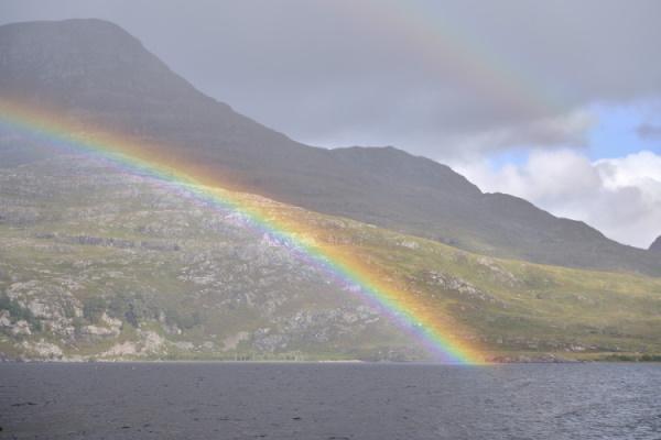 A rainbow over a loch with mountains in the background