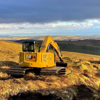 Digger digging up peatland on a hill