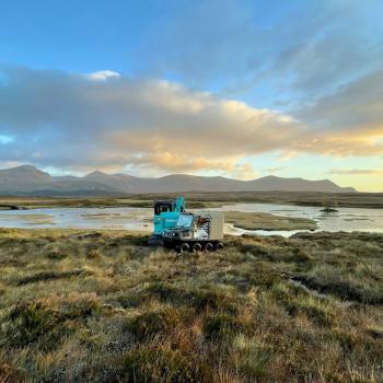 Restoration machinery on peatland with river and hills in the background