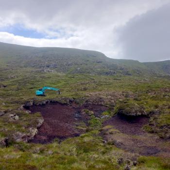 Digger restoring peatland on a hill
