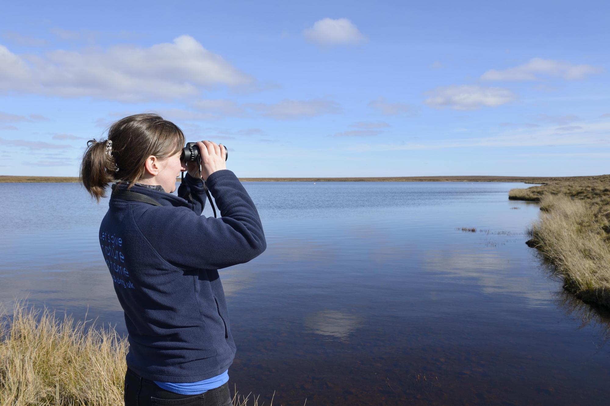 lady looking through binoculars out to sea